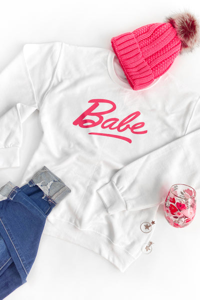 White Sweatshirt with Barbie Inspired "Babe" Text On Front with Pink Beanie and Jeans