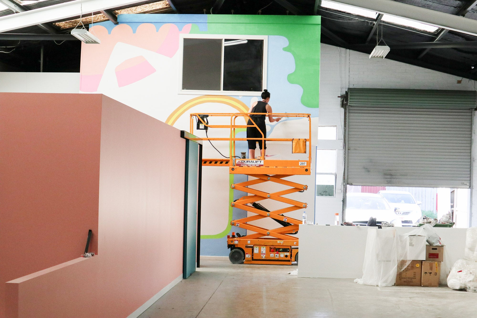 Deb McNaughton Artist - working on Massive wall mural - painting on forklift - Zudis -  Melbourne