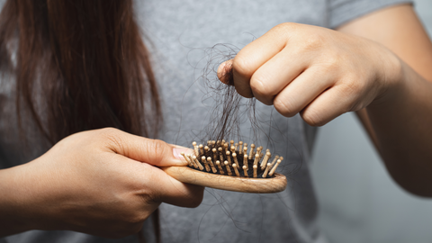 image of a women pulling shedding hair out of brush