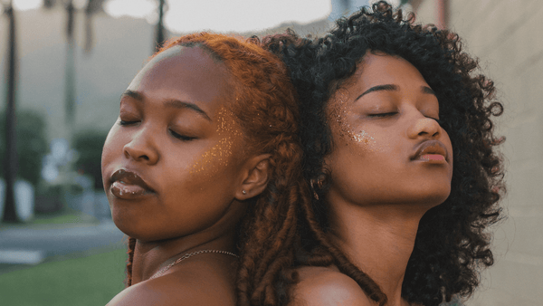 Two american african woman close eyes with beautiful curly and braided hair