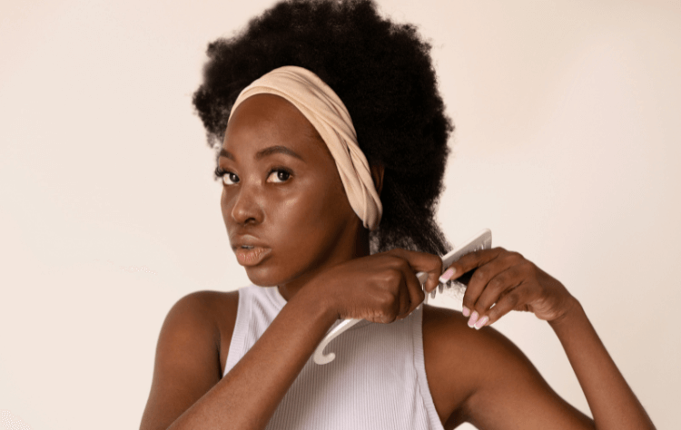 Black woman using hair comb on her afro hair side view