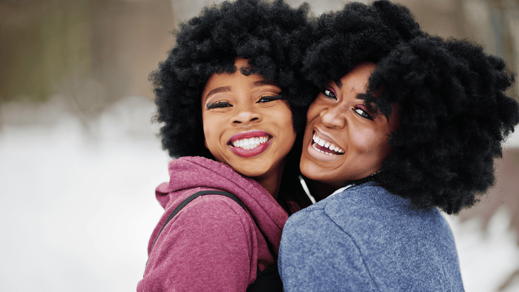 two african american woman with natural curly hair hugging