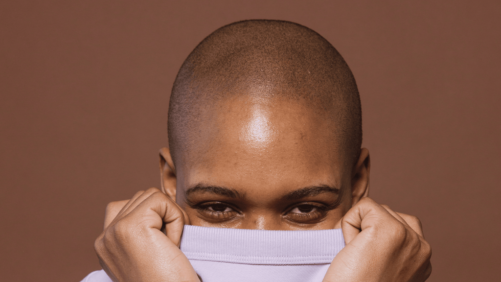 Bald african american woman covering her face
