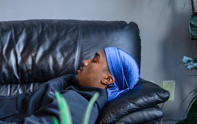 african american man wearing blue durag sleeping in the couch
