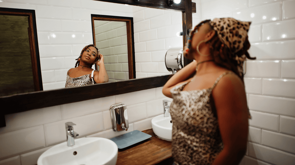 Lovely african american woman with dreadlocks in leopard outfit looking in the mirror