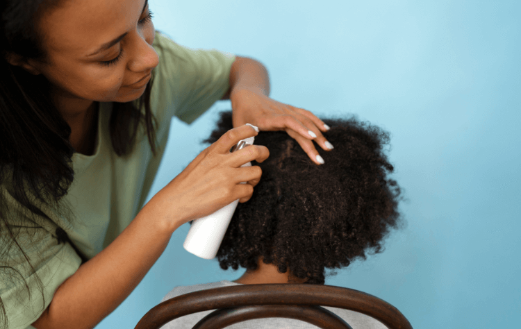 Mom helping a young black girl by putting hair product