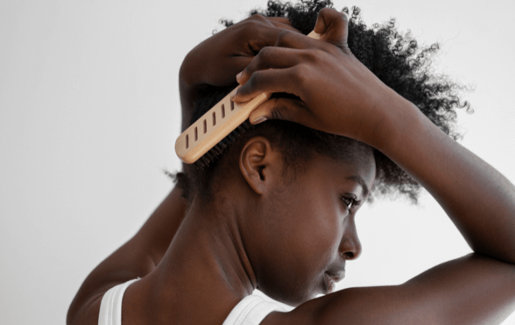 Side view young black woman brushing curly hair