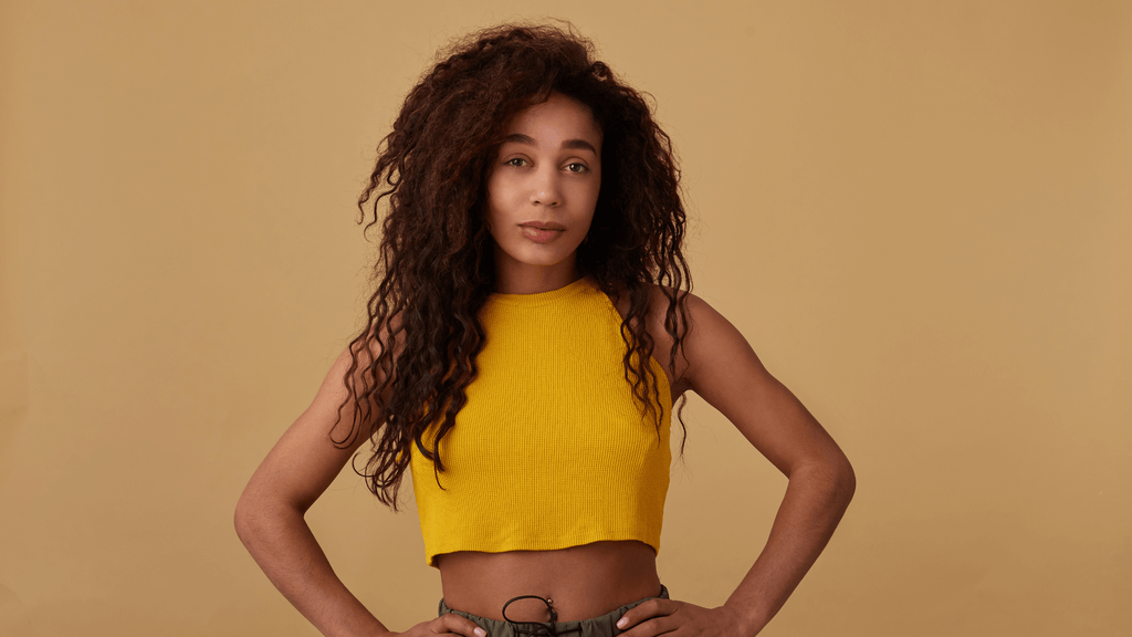 A woman wearing a yellow croptop with a big and long hair
