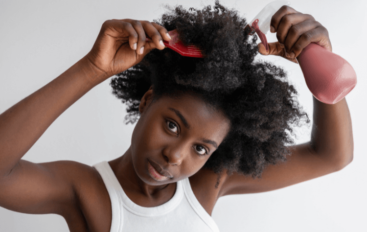 medium shot african american woman arranging hair while applying hair product on her curly hair