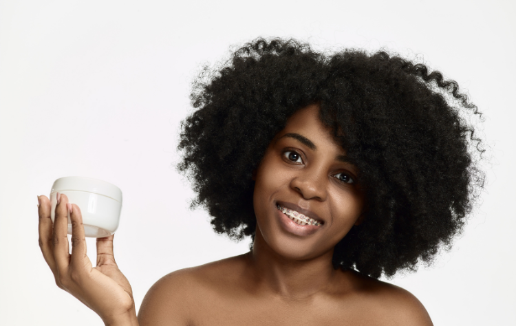 portrait young smiling black woman holding moisturiser container