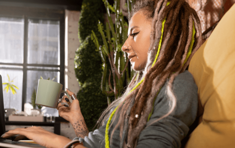 side view light skinned dreaded woman reading cafe holding coffee