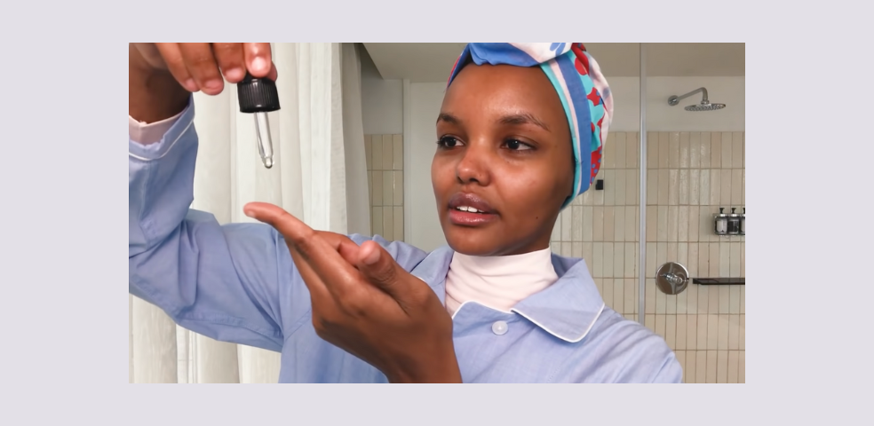 Model Halima Aden using a facial oil