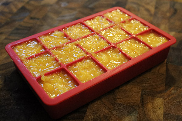 Closeup of silicone ice tray with peach puree inside.
