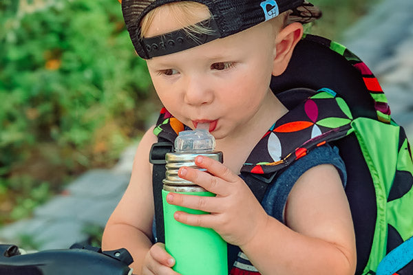 Toddler wearing a baseball cap drinking from a sustainable Pura water bottle.