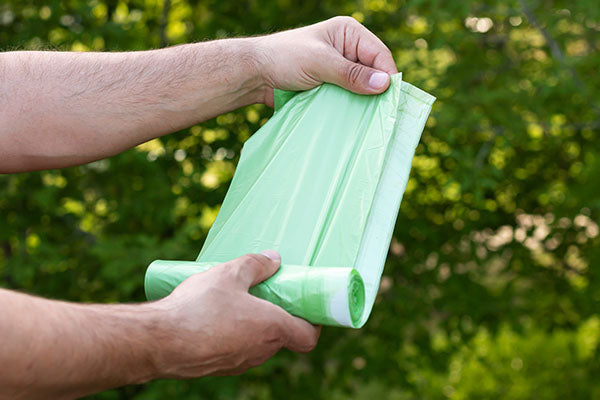 Man’s hands holding compostable bags in nature.