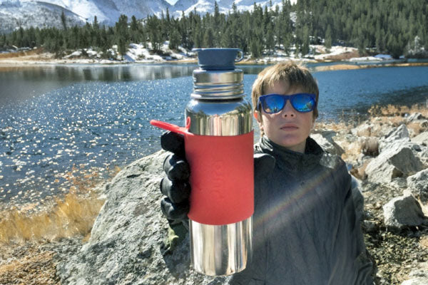 A child using a Pura Stainless plastic-free water bottle while camping.