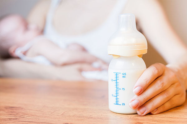 Mother feeding her infant with a plastic baby bottle.