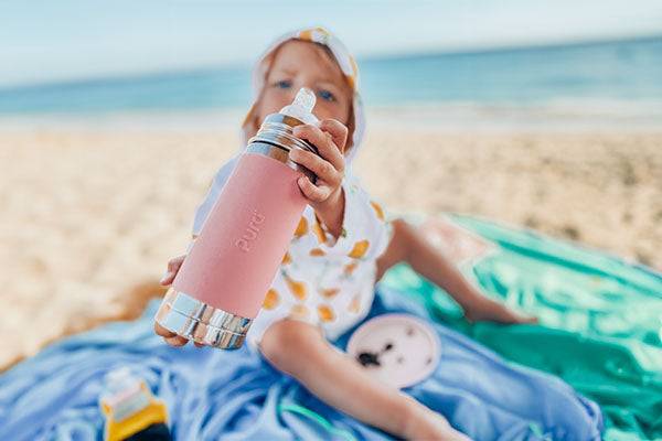 Young toddler holding a Pura Stainless plastic-free baby bottle.