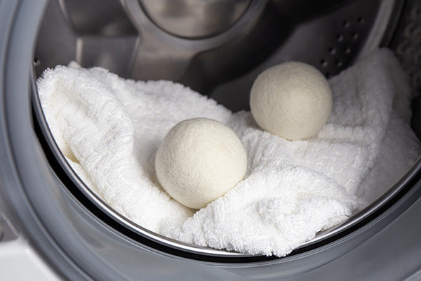 Two wool dryer balls laying in a laundry dryer machine.