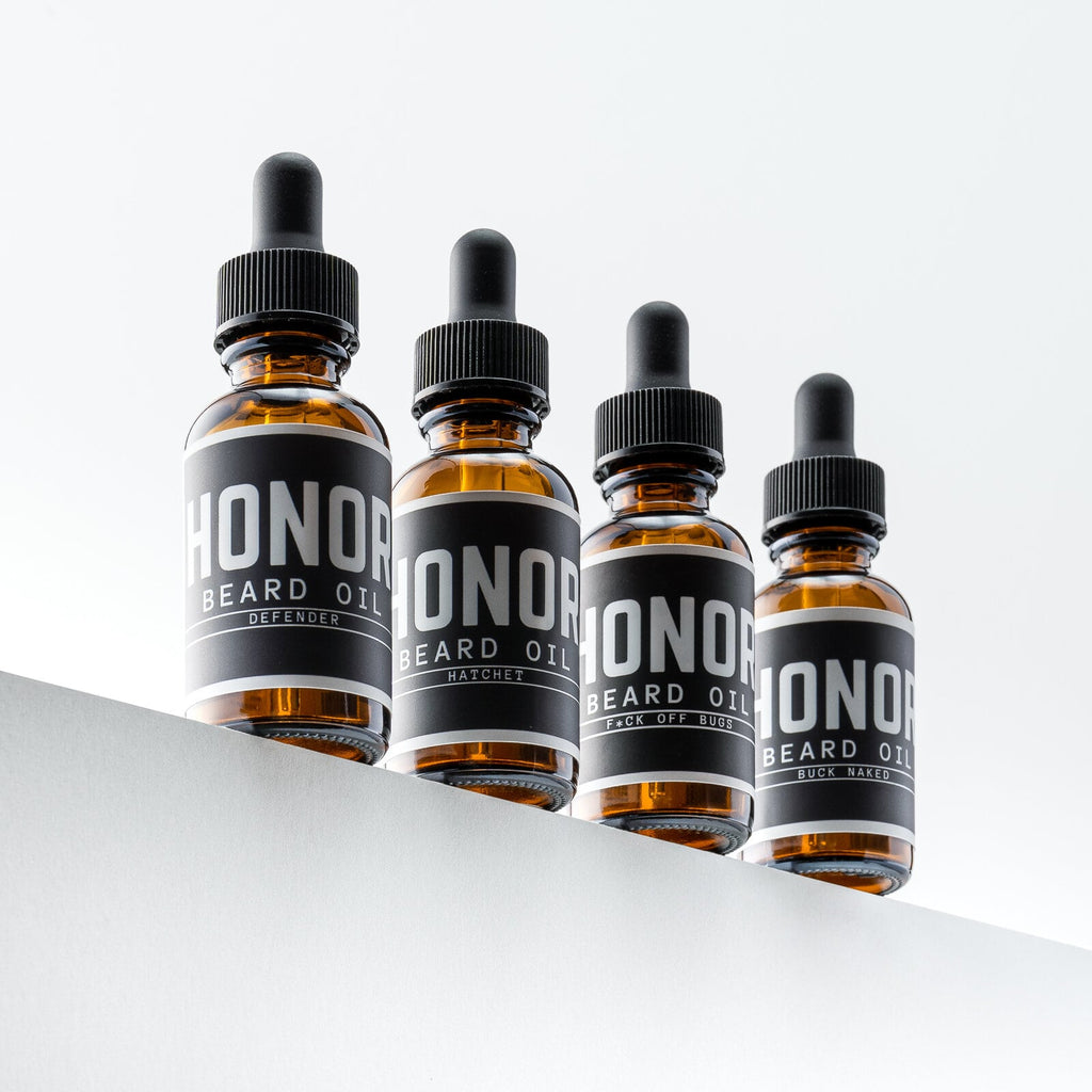 Four beard oil bottles on white background