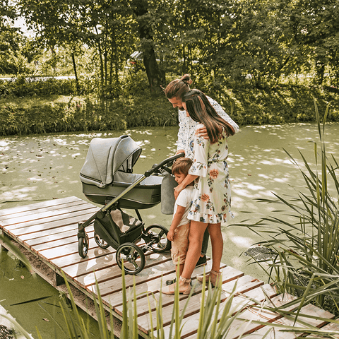 Eltern mit Kinderwagen auf einem Steg am Fluss