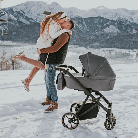 Glückliche Eltern in winterlicher Landschaft mit dem Kinderwagen Paradise Baby VR