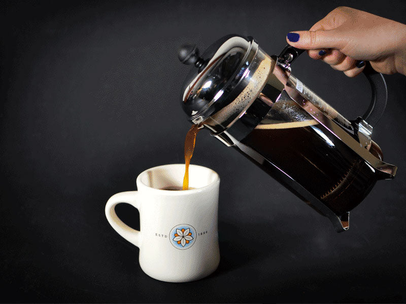 How to use a French Press - A photo of coffee being poured out of a French Press into a coffee mug.