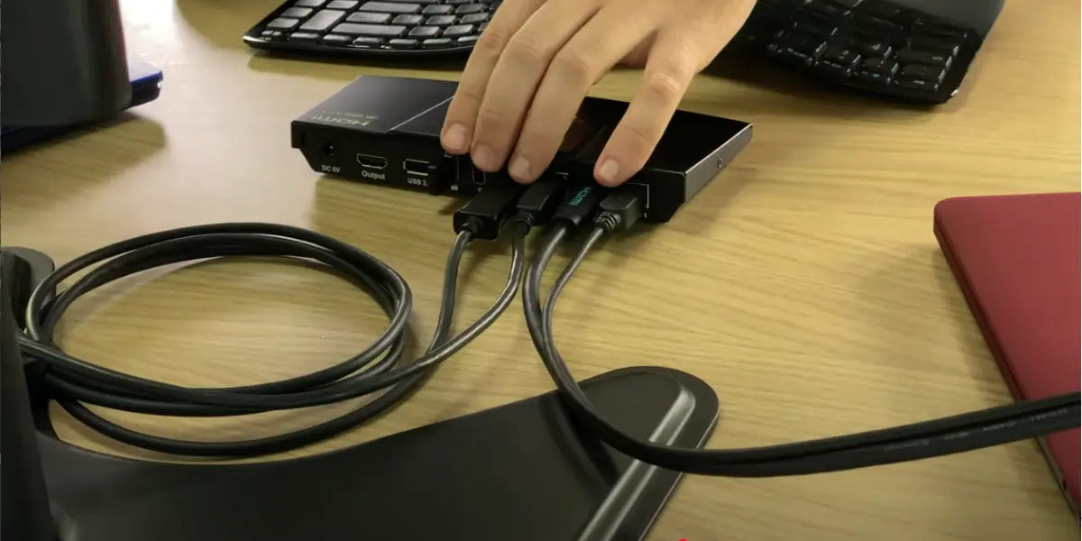 Close-up of a KVM switch showing HDMI output and USB 2.0 connections used to share one monitor and USB devices between two computers.