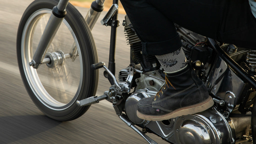 Person riding motorcycle wearing black moc-toe boots