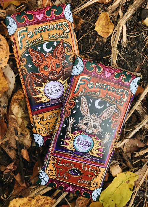 Image of 2020 Halloween Trick or Treat Limited Edition chocolate bar collaboration with Linda Ritter formerly of Salgado Fenwick. Wrapper features halloween design inspired by zoltar fortune teller with illustrated bat and bunny. Product features fortune card and milk chocolate with pop rocks, jujube candies and sprinkles.