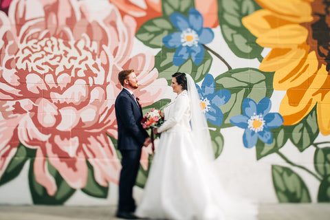 Image of wedding couple from 2020 featuring outfits by Derks Formal and Novelle Bridal standing in front of the mural at Manchester Square painted by artist Alixandra Jade based in Edmonton, Alberta, Canada. Photo credit: Sarah Mavro Photography