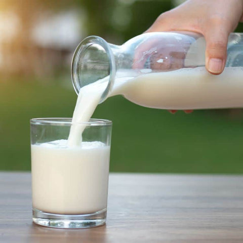 Milk from a bottle being poured into a mug