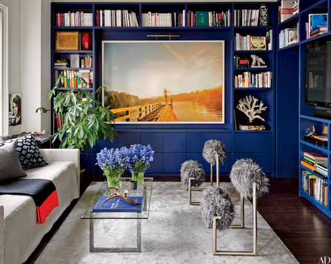 Living room with blue bookshelves and artwork with attached picture light