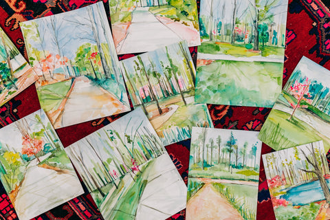 Landscape watercolor artworks laid out on the floor.