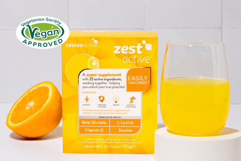 Zest Active in a kitchen counter with the Zest Active Drink and half an orange, Vegan Approved Logo