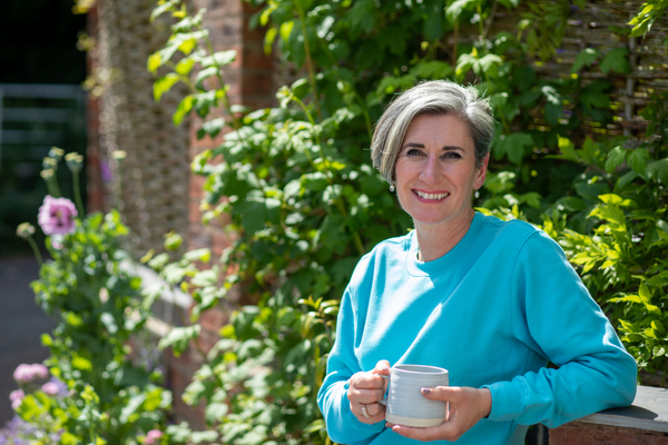 Wendy Hill a Naturopathic Nutritional Therapist stood outdoors holding a cup of tea