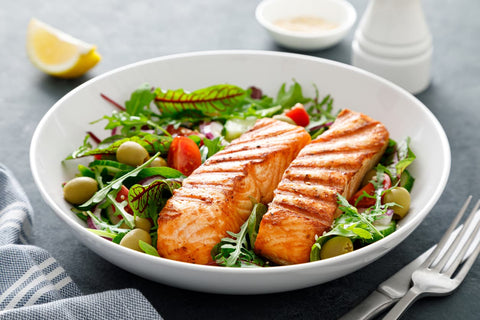 A bowl of greens, olives, tomatoes and grilled salmon – this meal is part of the Mediterranean diet, which is good for brain health.