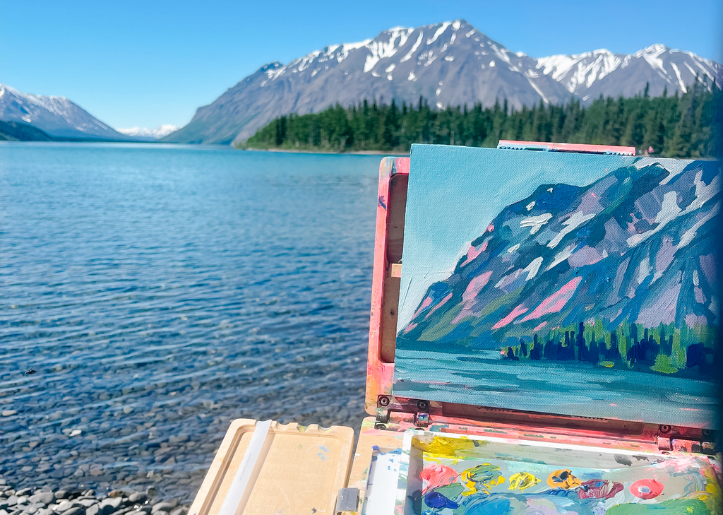 A small painting of a mountain being created on location in front of a lake