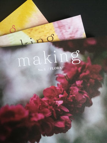 three magazines on top of each other with a black background. The magazine is called making magazine and is titled no.1 / Flora. it has a picture of a dark pink garland on the front of it with a blurred background. it is very simple. 