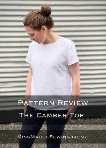 an image of a white girl with brown hair wearing a white woven t-shirt with the words Sewing pattern review The Camber Top from Merchant and Mills