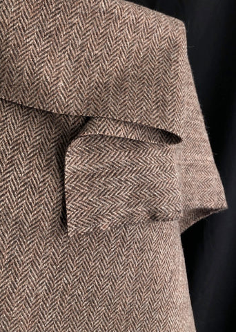 A soft brown and Carmel and beige herringbone tweed draped over a dressmakers dummy with a black background