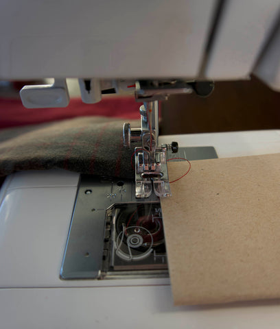 a picture of the front of the machine, close up to the foot. the cardboard is at the side and the fabric at the back.