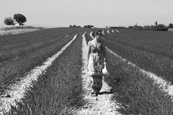 a black and white image of a pakeha woman walking though a field of lavender 