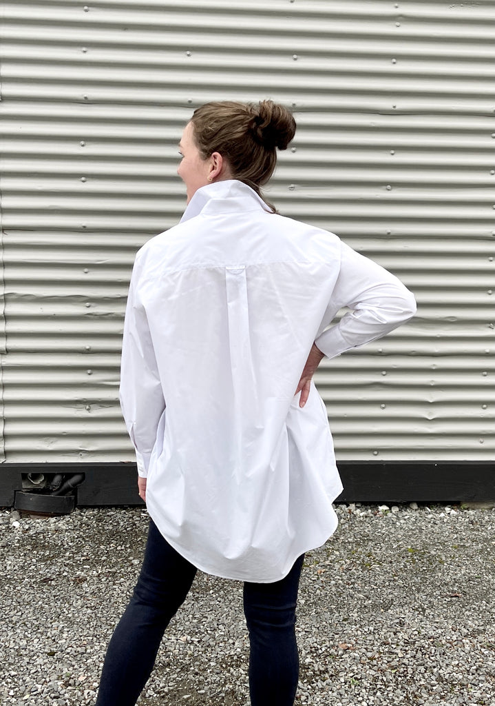 woman standing with back to camera wearing a white cotton oversized shirt