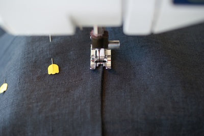 A close up of a sewing machine foot sewing close to the edge of the pocket 