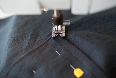 a close up of the needle and the sewing foot pivoting on the corner of the apron