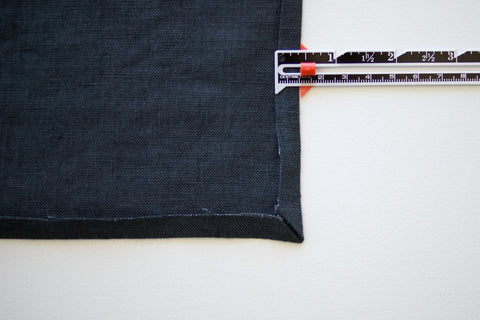a blue denim square with the side folded up and a sewing measuring gauge showing the distance of 1cm