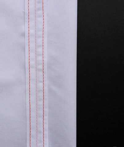 a white pice of fabric to the right hand side with orange straight stitching on the seams on the right hand edge with a black background