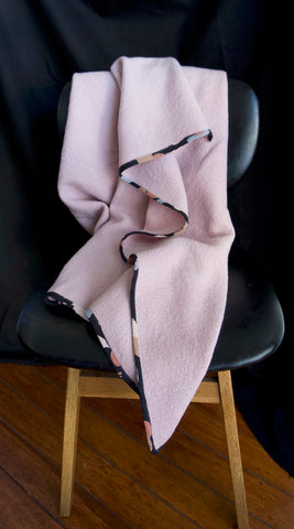 a heavy woollen blanket draped over a chair with a black seat and wooden legs. It has a black background