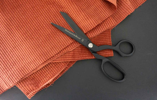 a pair of black scissors on a brick coloured cord